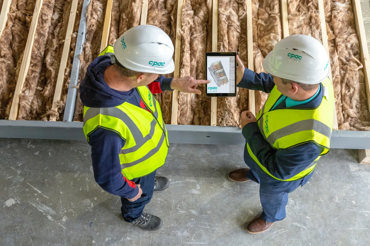 Handwerker erfasst auf der Baustelle einen Rapport mit dem Smartphone.